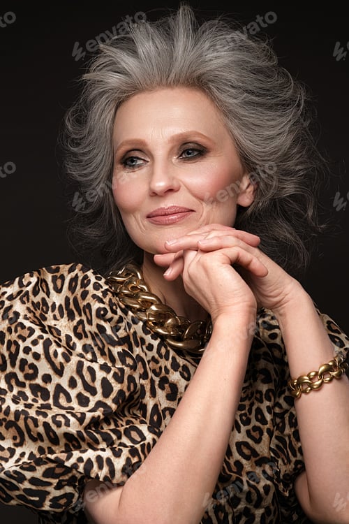 Preview: Portrait of a beautiful elderly woman in a leopard blouse with classic makeup and gray hair.