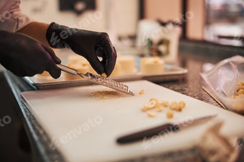 Preview: Qualified confectioner grating hazel-nuts on a cutting board