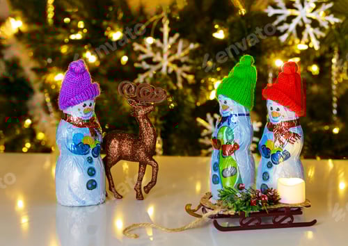 Preview: Snowman standing in front of Christmas tree made of milk chocolate with deer.