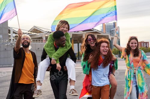 Preview: Excited people at a pride festival, in piggybacks holding rainbow flags celebrating the pride month.
