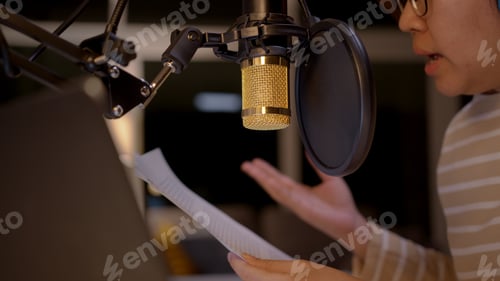 Preview: Asian female podcaster recording and broadcasting her podcast from home.