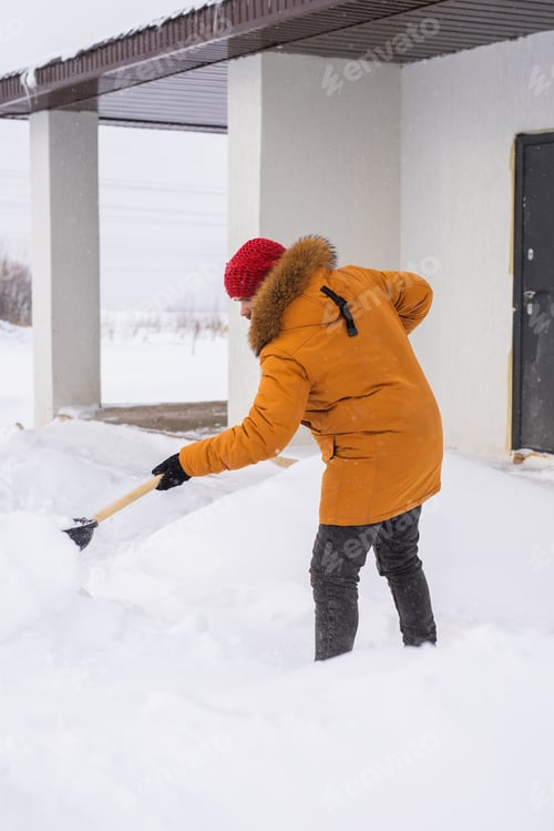 Preview: A man cleans and clears the snow in front of the house on frosty day. Cleaning the street from snow