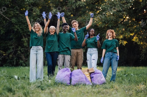 Preview: Group of volunteers raising hands celebrating in park after cleaning