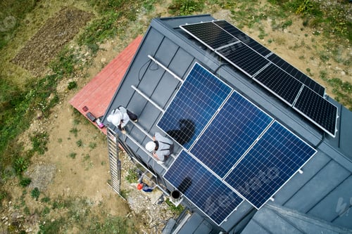 Preview: Workers lifting up photovoltaic solar module while installing solar panel system on roof of house.