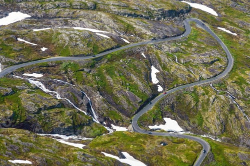 Preview: Winding road in a green landscape with snow patches