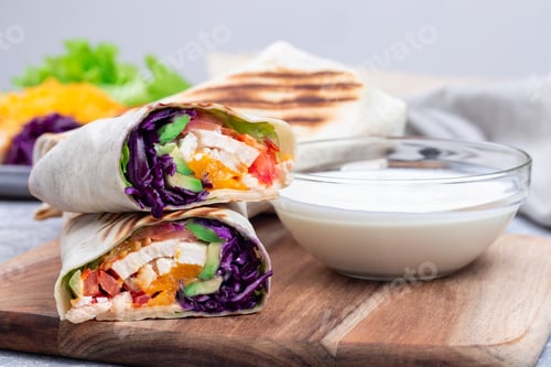 Preview: Grilled chicken wraps with red cabbage, avocado, tomato, lettuce and cheddar cheese, on wooden board