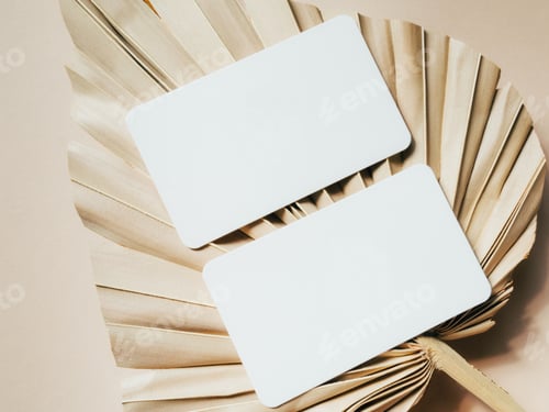 Preview: Two blank white cards on a beige dry palm leaf background top view