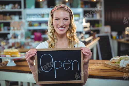 Preview: Portrait Of Smiling Waitress Showing Chalkboard With Open Sign In Caf?