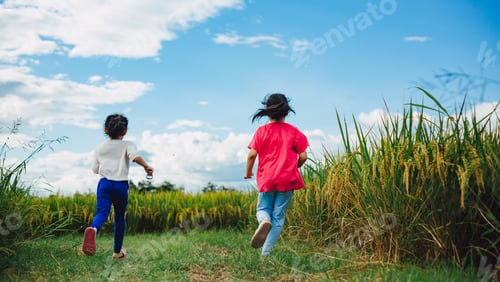 Preview: Cheerful little children play and outdoor running in the green field under blue sky. Concept for hap
