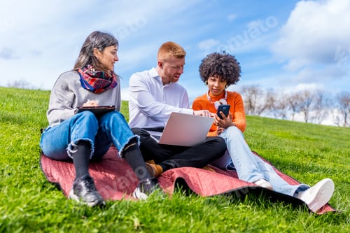 Preview: Students working on devices in park on sunny day