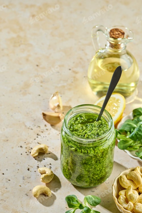 Preview: Fresh homemade green sprout pesto in glass jar on sunny kitchen table with ingredients