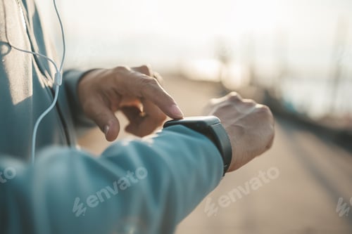 Preview: sport man checking at smartwatch during training and running in the park.