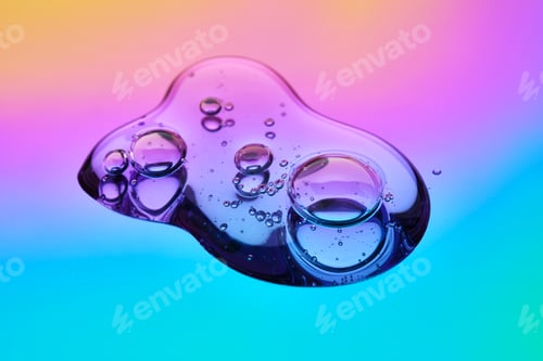 Preview: A drop of cosmetic serum on a multicolored background in shades of blue and lilac.