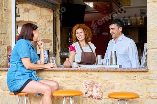 Preview: Couple working at the bar in an outdoor cafe talking to a female client