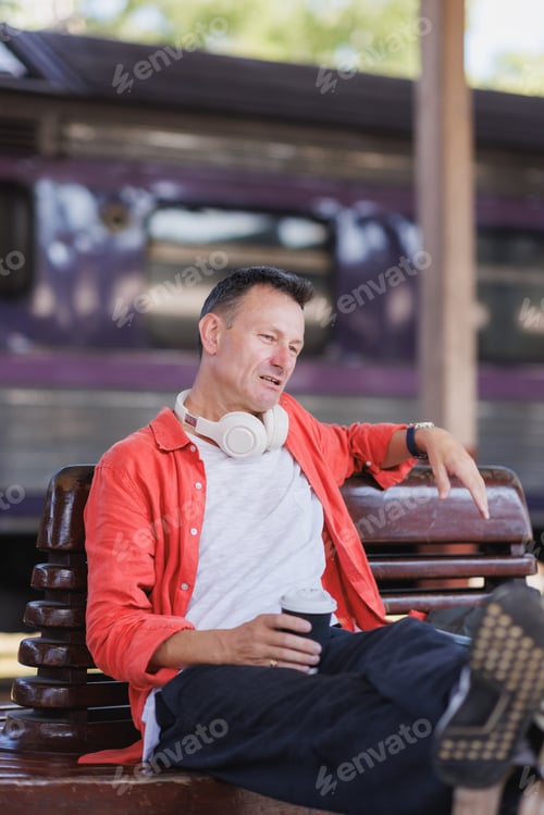 Preview: Man relaxing at train station bench enjoying coffee
