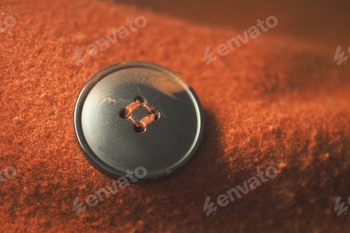 Preview: Black button on a brown fabric surface with soft texture