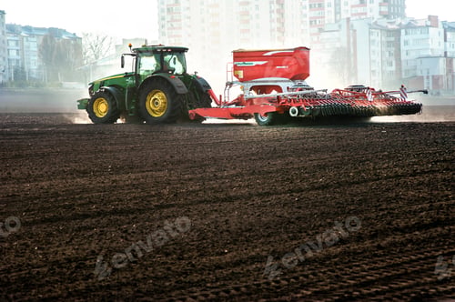 Preview: Farmers fertilize and sow, tractor with seeder with fertilizer at the field within the city