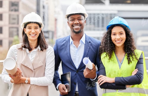 Preview: Cropped portrait of three young engineers standing with blueprints on a construction site