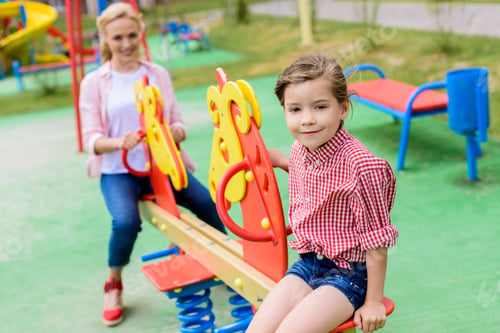 Preview: selective focus of adorable little child sitting on rocking horse while her mother sitting behind at