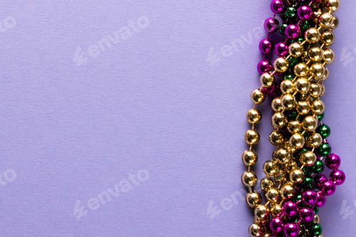 Preview: Composition of colourful mardi gras beads on lilac background with copy space
