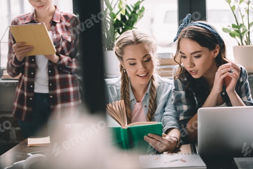 Preview: Young beautiful women students studying with devices and book