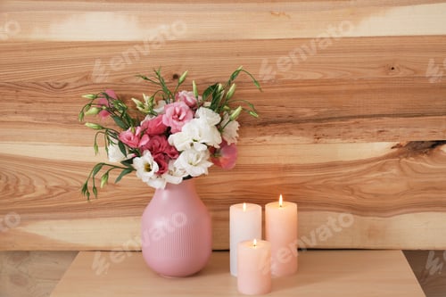 Preview: Burning candles and vase with flowers on table against wooden wall