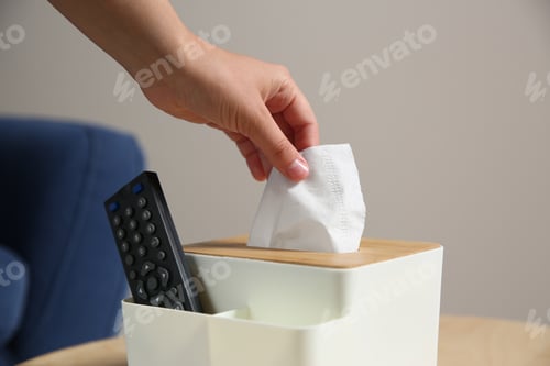 Preview: Woman taking paper tissue out of box on wooden table at home, closeup