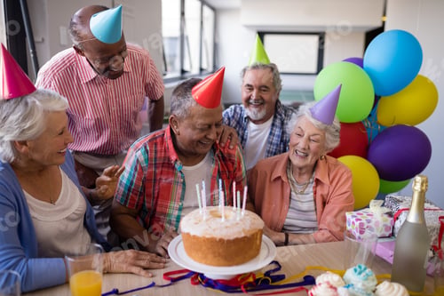 Preview: Happy senior friends by birthday cake at party