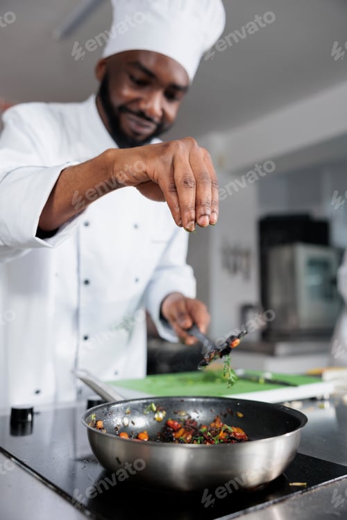 Preview: Head cook throwing fresh chopped herbs in pan to improve taste of meal while in professional kitchen
