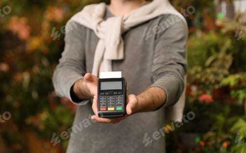 Preview: Man holding payment terminal in floral shop, closeup