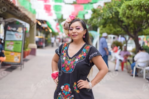 Preview: Mexican woman wearing traditional dress with multicolored embroidery celebrating independence day.