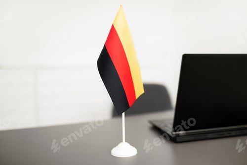Preview: Flag Of Germany Standing Near Laptop On Desk In Office