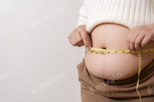 Preview: An obesity using measuring tape to show the real size. Chubby fat woman using measure tape at belly.