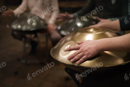 Preview: A musician's hand playing the handpan with other people.