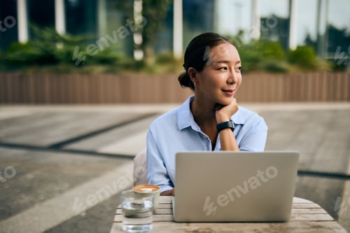 Preview: Asian Business Woman Relaxing Outside With Laptop, Coffee, and Contemplative Mood