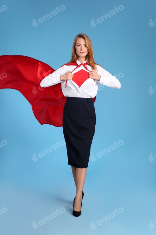 Preview: Confident businesswoman wearing superhero costume under suit on light blue background