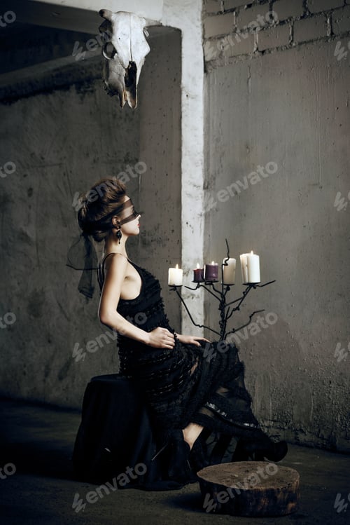 Preview: Pale girl with retro style hair in long witch dress with lace face mask in mystical castle