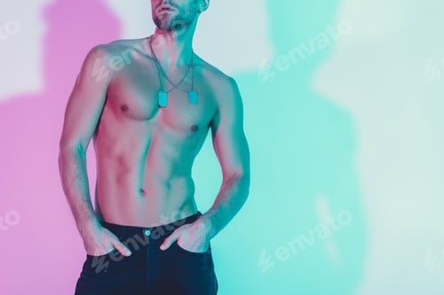 Preview: cropped view of sexy shirtless man in dark blue jeans holding hands in pockets on background with