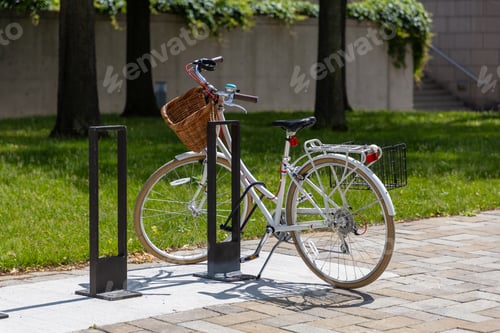 Preview: Bike parked at biking rack on the sidewalk. Retro bicycle with wicker basket.