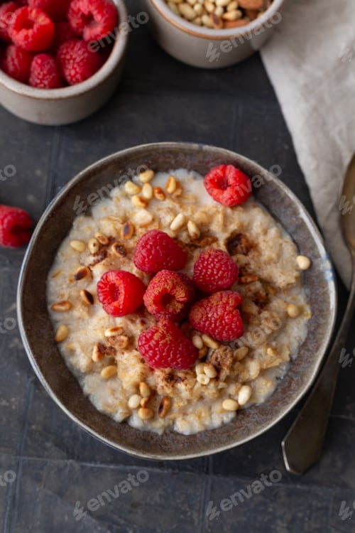 Preview: Oatmeal porridge with raspberries in a bowl and nuts. Healthy diet breakfast