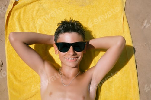 Preview: Teenage boy lying on the towel on a fabulous day at the beach.
