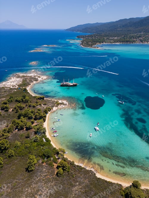 Preview: Aerial view of a coastal landscape with turquoise waters, sandy beaches, and a sailing ship anchored