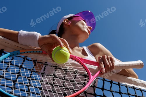 Preview: Modern female tennis player with racket and ball at the net under clear sky