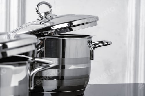 Preview: Aluminum cookware on black induction stove against grey wall