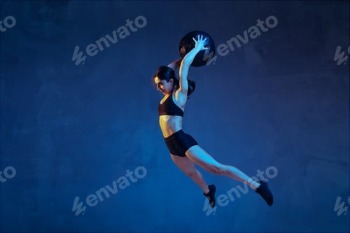 Preview: Caucasian young female athlete practicing on blue studio background in neon light
