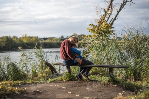 Preview: Mother hugging boy outdoors on the bench. Precious moments between mom and son