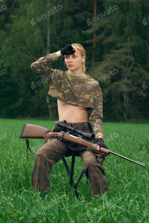 Preview: Attractive hunter girl with hunting carbine looking out the trophy