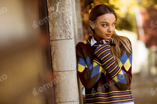 Preview: Young woman standing outside at sunny autumn day