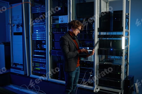 IT technician using digital tablet while working in data center with server rack