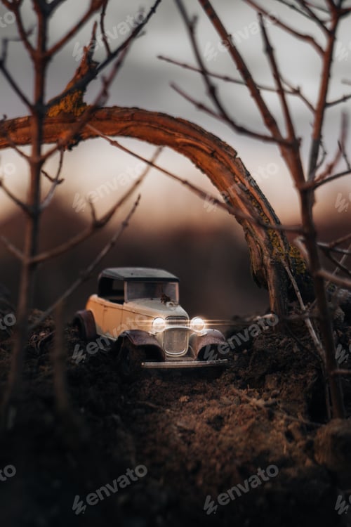 Preview: Vertical closeup of a toy vintage car in a forest with a blurry background